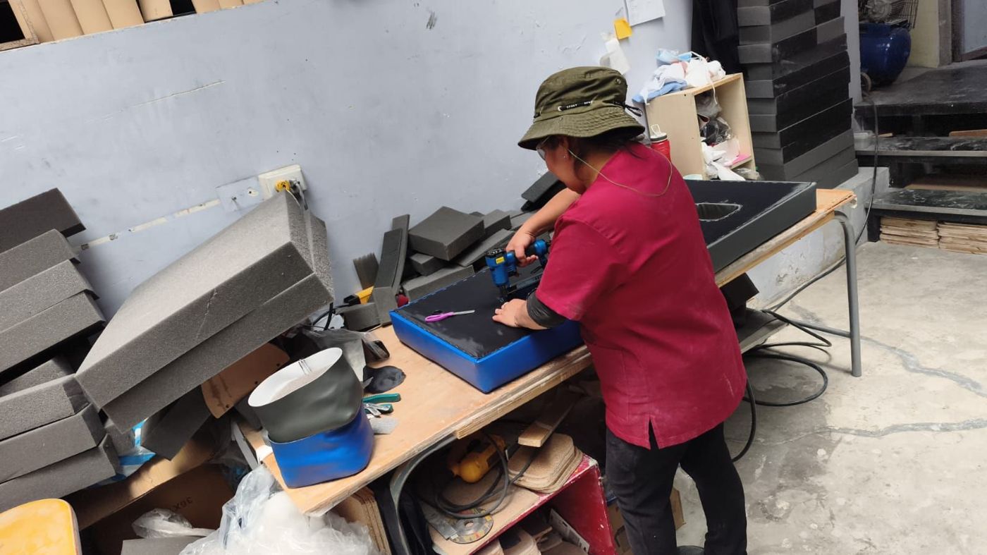 Trabajadora tapizando el colchón de una camilla en color azul